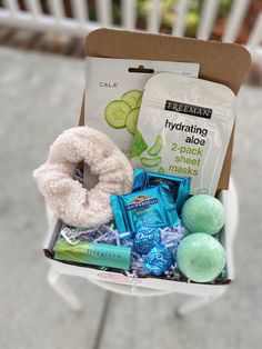 an open box with various items in it sitting on a white chair next to a fence