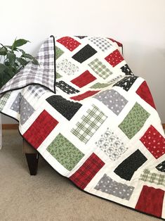 a quilted blanket sitting on top of a wooden bench next to a potted plant