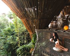 a woman sitting on top of a hammock in the jungle