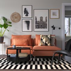 a living room with orange couches and pictures on the wall above them in black and white