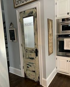 an old door is opened to reveal a kitchen with white cabinets and stainless steel appliances