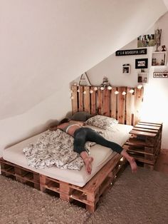 a woman laying on top of a bed made out of pallets