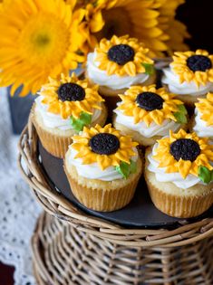 cupcakes with frosting and sunflowers are on a wicker basket