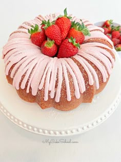 a bundt cake covered in icing and strawberries sits on a white plate