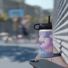 a coffee cup sitting on top of a wooden bench next to a cell phone holder