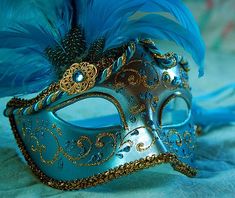 a masquerade mask with blue feathers and words written on the side that reads, attend a masquerade