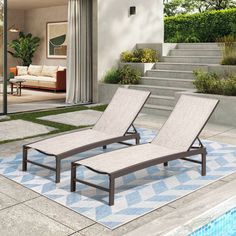 two lounge chairs sitting on top of a blue and white rug next to a swimming pool