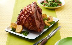 a large piece of meat sitting on top of a white plate next to green plates