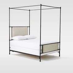 an iron bed frame with white linens and pillows on the bottom, against a gray background