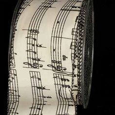 a roll of music notes printed on a white and black grosgraam ribbon