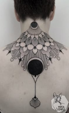 the back of a man's neck with an intricate tattoo design on his chest