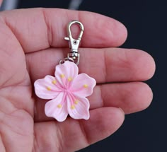 a hand holding a pink flower shaped keychain