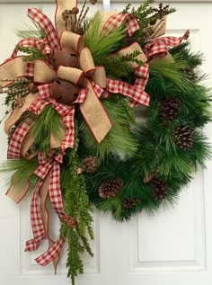 a christmas wreath hanging on the front door with pine cones and burlucks