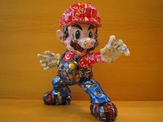 a paper mache character wearing a red helmet and holding his hand out to the side