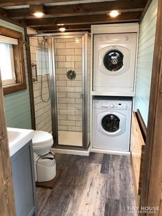 a washer and dryer in a small bathroom with wood flooring on the walls