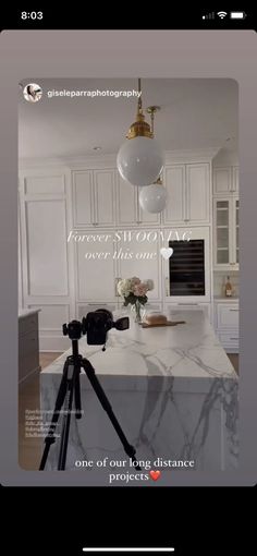 a camera is set up in front of a kitchen island with marble countertops and white cabinets