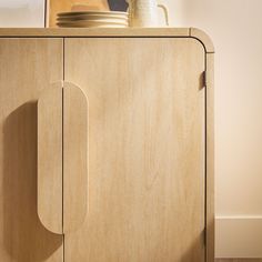 a close up of a wooden cabinet with a plate on it and a vase in the background