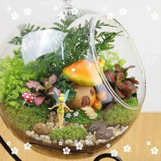 a glass bowl filled with plants and small figurines