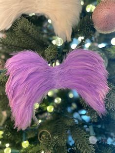 a purple feather ornament hanging from a christmas tree