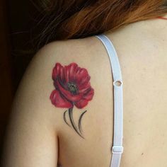 a woman with a red flower tattoo on her upper back shoulder and arm, behind her is a white bra