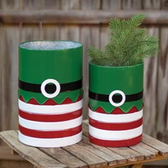 two green and red christmas planters sitting on top of a wooden table