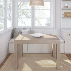 a kitchen with white cabinets and wooden table in front of the window, next to a sink