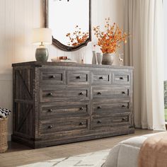 a large wooden dresser sitting in front of a window next to a lamp and mirror