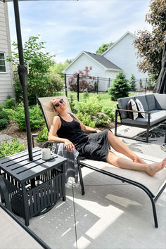 a woman laying on top of a chair under an umbrella next to a black table