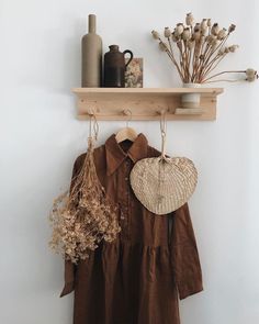 a wooden shelf with some dried flowers and other items hanging on it's side