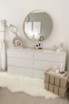 a bedroom with white furniture and a round mirror on the wall over a dresser next to a bed