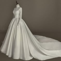 a white wedding dress on display in front of a gray background with an object to the side