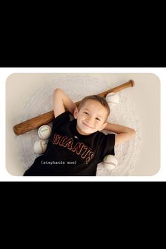 a young boy laying on top of a white doily with baseballs and bats