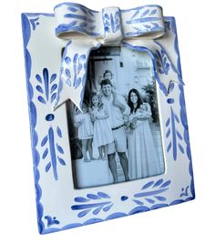 a blue and white photo frame with a bow on the front that has an image of three women in dresses