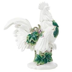 a white rooster statue with green leaves on it's back and wings spread out