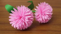 two pink flowers sitting on top of a wooden table