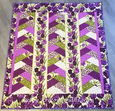 a quilted wall hanging with purple flowers and green leaves on the bottom half of it