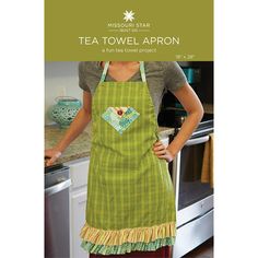 a woman wearing an apron in front of a kitchen counter with the words tea towel apron written on it