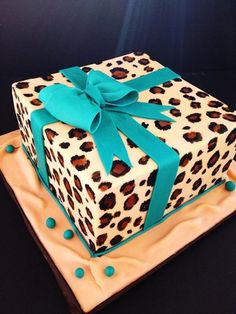 a square cake decorated with leopard print and blue ribbon