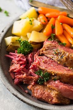 roast beef with carrots, potatoes and parsley on a plate next to other vegetables