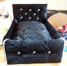 a black velvet chair sitting on top of a wooden floor