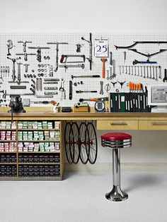 a workbench with many tools on the wall and two stools in front of it