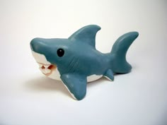 a blue and white shark figurine with its mouth open on a white surface