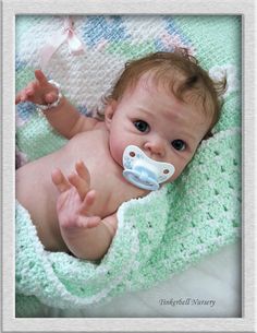 a baby laying on top of a blanket with a pacifier in it's mouth