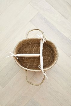 a woven basket on the floor with two handles and one handle is holding a pair of scissors