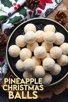 pineapple christmas balls in a black bowl on top of a table with pine cones