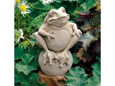 a frog statue sitting on top of a rock