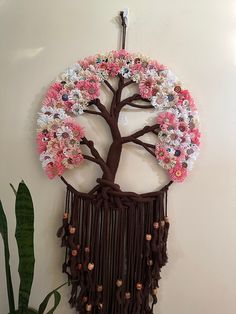 a wall hanging with a tree made out of flowers and fringes on it's side