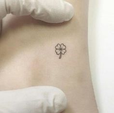 a small clover tattoo on the back of a woman's stomach