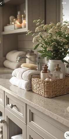 a bathroom counter with towels, soaps and flowers in a basket on top of it