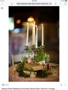 a table topped with candles and flowers on top of a wooden table covered in greenery